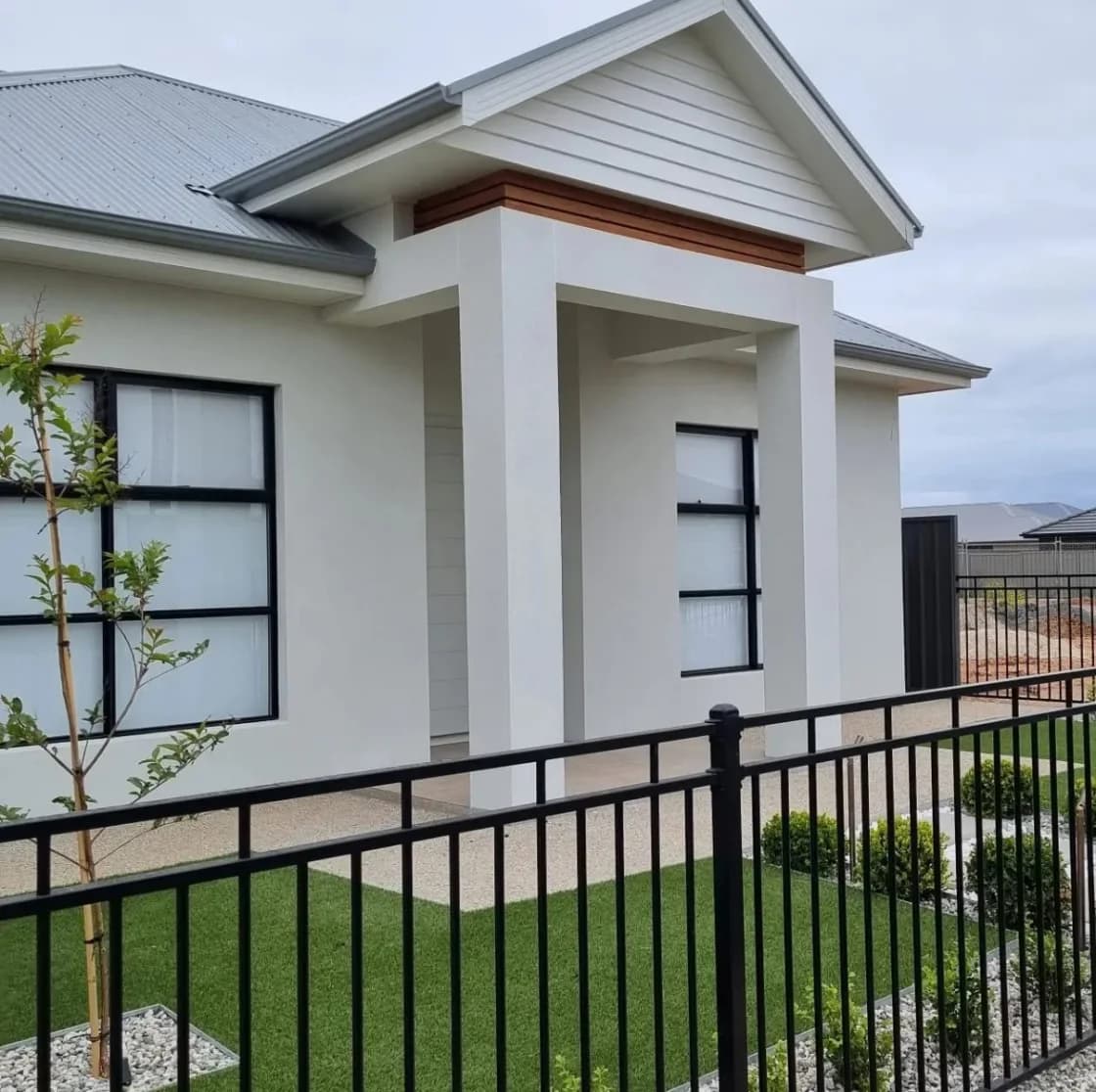 Finished front entry portico with rendered columns and a timber-lined gable