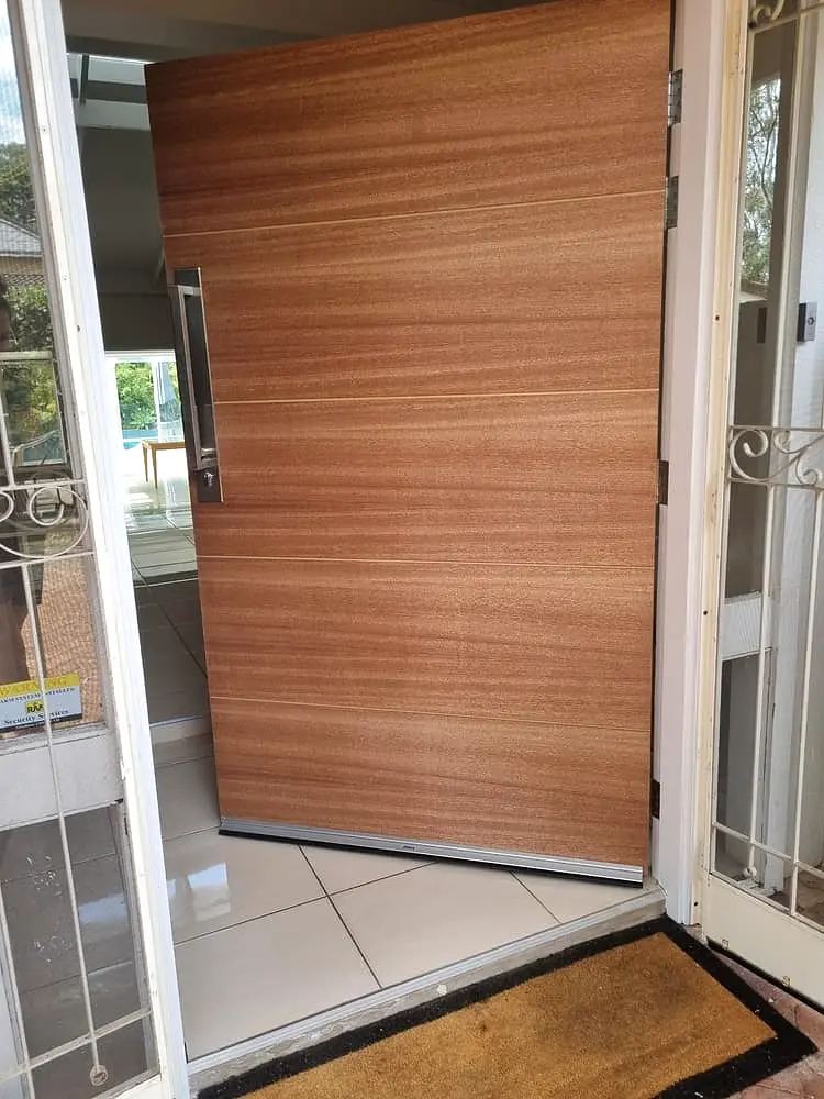 Finished vertical-timber pivot entry door to a home